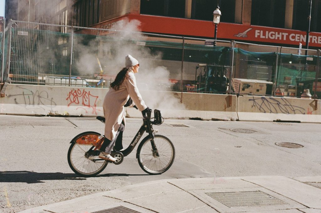 Woman rides a bike through steam on city street