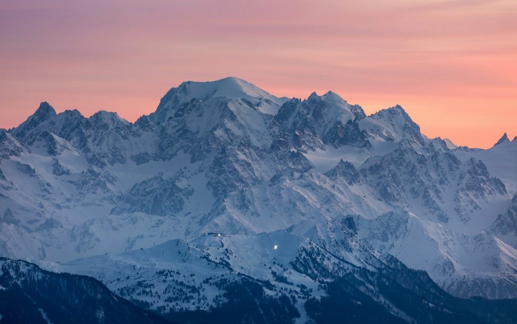 Snow-capped mountains under a vibrant pink and orange sunset sky.